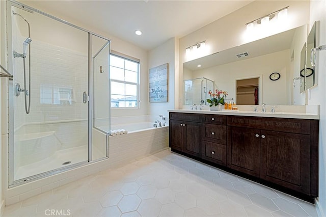 bathroom featuring visible vents, a garden tub, a sink, a shower stall, and double vanity