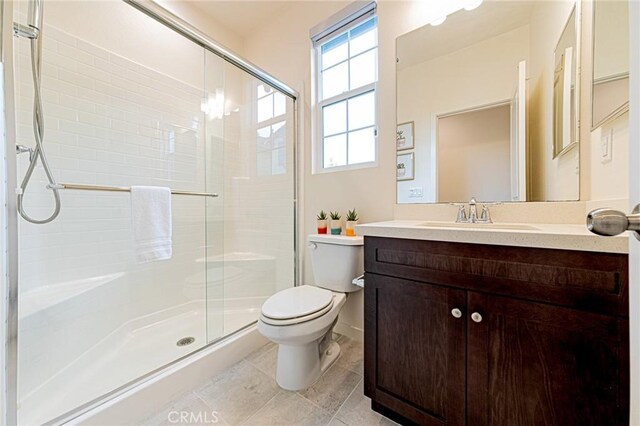 full bath featuring vanity, a shower stall, toilet, and tile patterned flooring