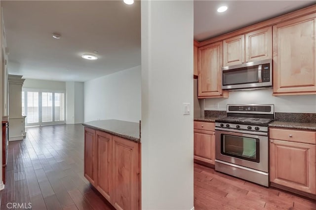 kitchen with dark countertops, light wood finished floors, stainless steel appliances, and open floor plan