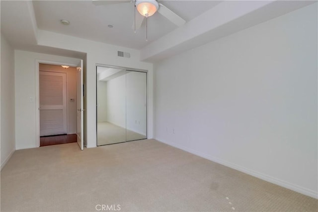 unfurnished bedroom featuring ceiling fan, light carpet, visible vents, baseboards, and a closet