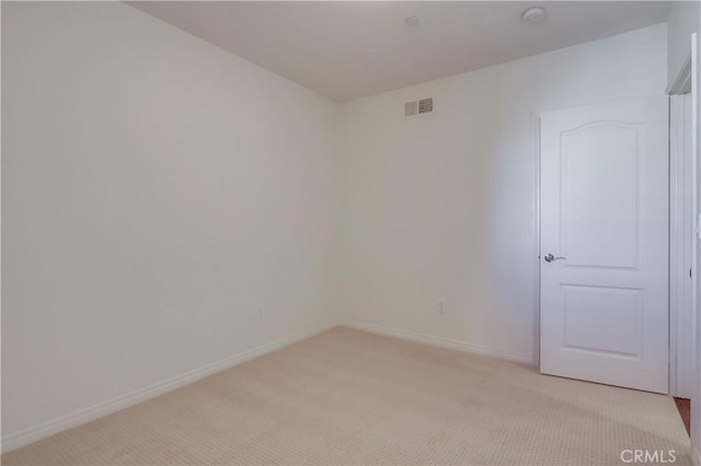 empty room featuring light carpet, visible vents, and baseboards