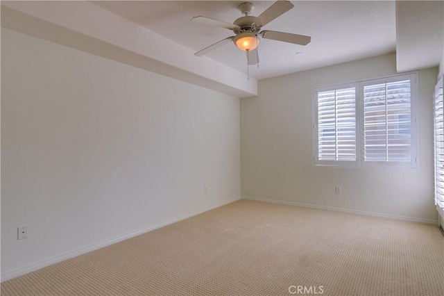 spare room featuring baseboards, a ceiling fan, and light colored carpet