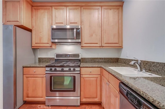 kitchen with light brown cabinets, stainless steel appliances, and a sink