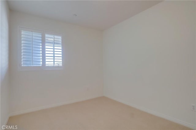 empty room featuring light carpet and baseboards