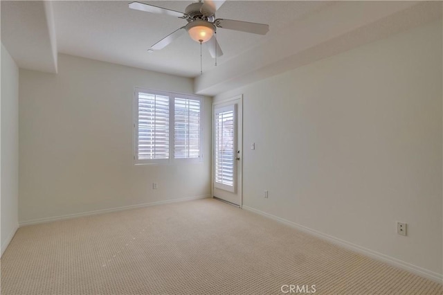 spare room featuring baseboards, a ceiling fan, and light colored carpet