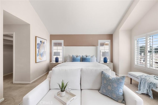 carpeted bedroom with a spacious closet, multiple windows, and vaulted ceiling