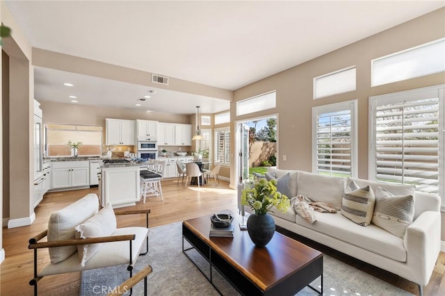 living room with light wood finished floors, visible vents, recessed lighting, and baseboards