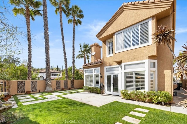 back of property with a patio area, stucco siding, french doors, and fence