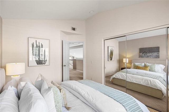 carpeted bedroom featuring visible vents, a closet, and vaulted ceiling