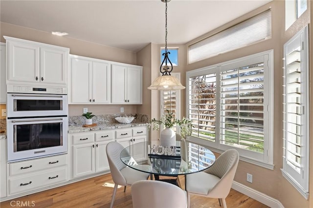 dining space with light wood-type flooring and baseboards