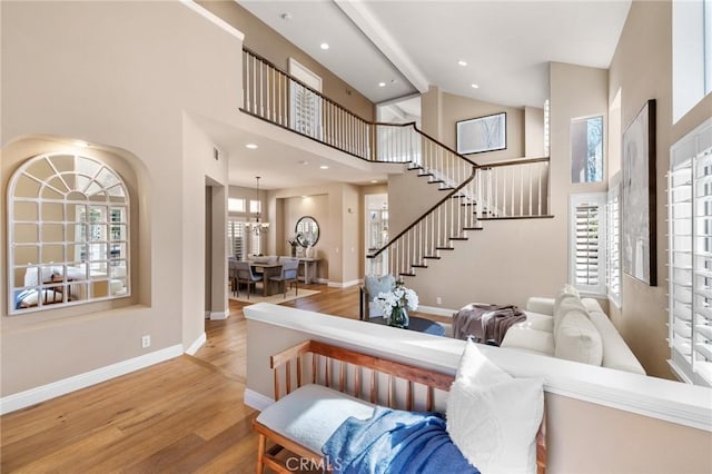 interior space with high vaulted ceiling, wood finished floors, recessed lighting, baseboards, and stairs