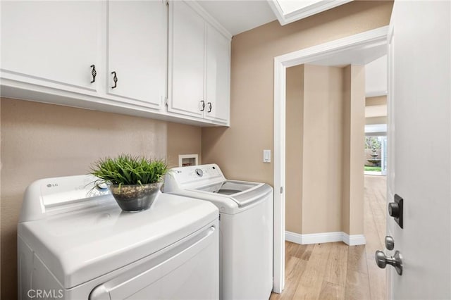 laundry room featuring washing machine and clothes dryer, light wood-style flooring, cabinet space, and baseboards