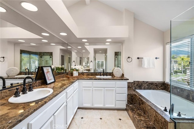 bathroom with a sink, a garden tub, double vanity, and vaulted ceiling