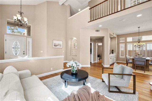 living area featuring visible vents, baseboards, a notable chandelier, and wood finished floors