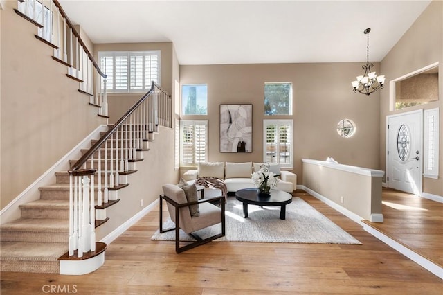 living room with hardwood / wood-style floors, a towering ceiling, a wealth of natural light, and a chandelier