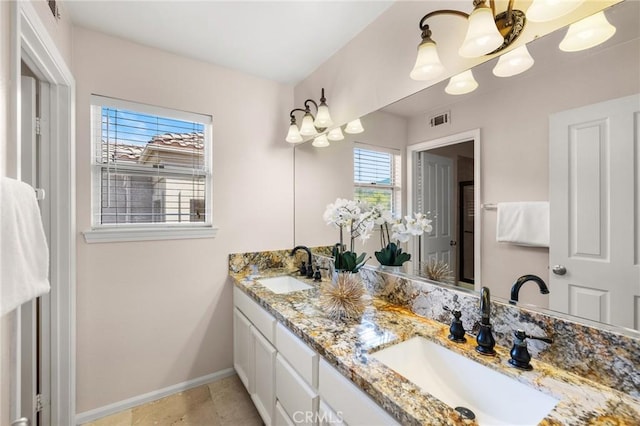 bathroom featuring a sink, visible vents, baseboards, and double vanity