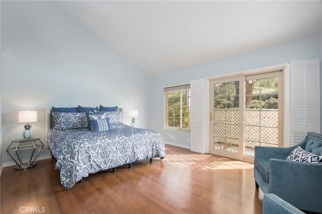 bedroom featuring access to exterior, lofted ceiling, baseboards, and wood finished floors