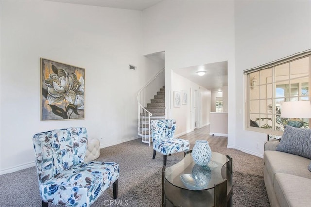 carpeted living area with a towering ceiling, baseboards, stairs, and visible vents