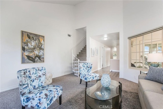 carpeted living area featuring visible vents, baseboards, stairs, and a high ceiling