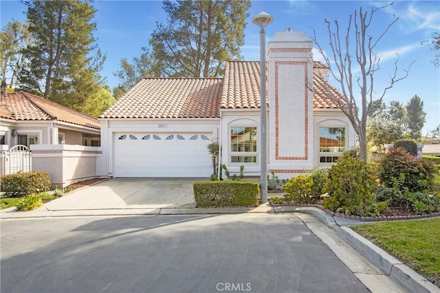 mediterranean / spanish home with a garage, fence, a tiled roof, driveway, and stucco siding