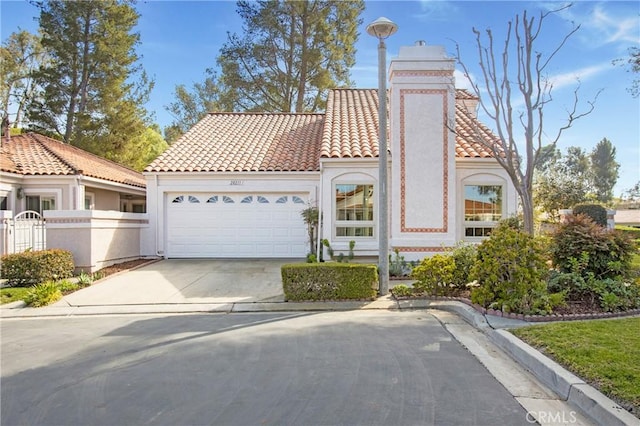 mediterranean / spanish home with a garage, a tiled roof, concrete driveway, stucco siding, and fence