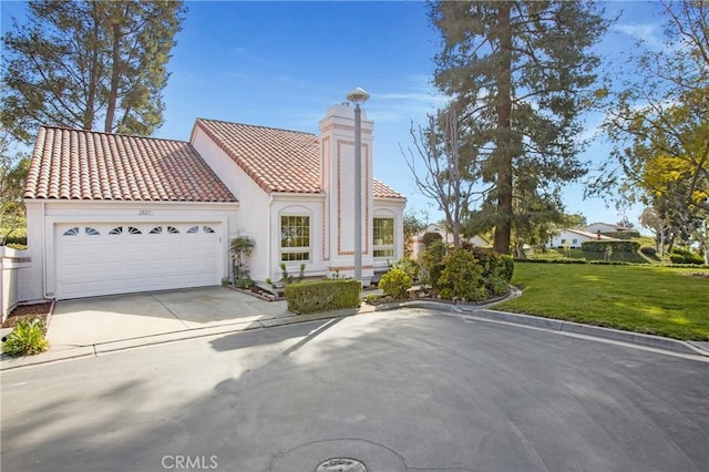 mediterranean / spanish-style home featuring an attached garage, a tiled roof, concrete driveway, stucco siding, and a front lawn