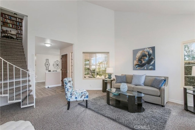 carpeted living area with a high ceiling, stairway, and baseboards