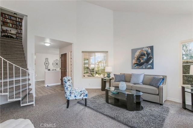 living room featuring a high ceiling, stairway, carpet, and baseboards