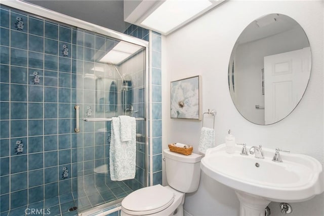 bathroom with a shower stall, toilet, and a sink