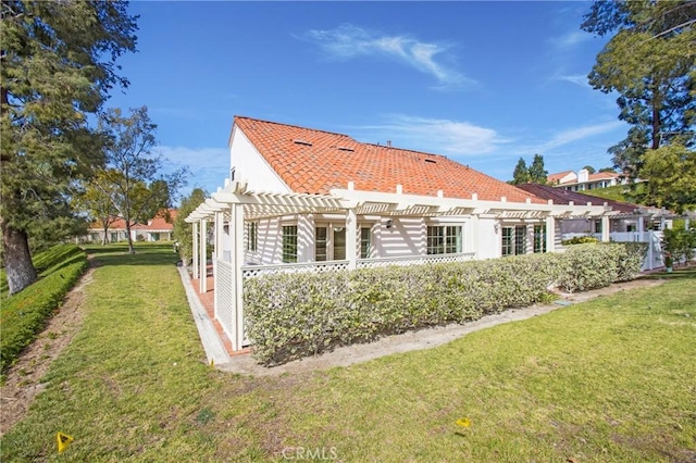 rear view of property featuring a lawn, a pergola, and stucco siding