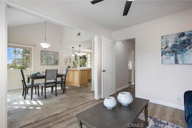 living area featuring lofted ceiling, baseboards, visible vents, and wood finished floors