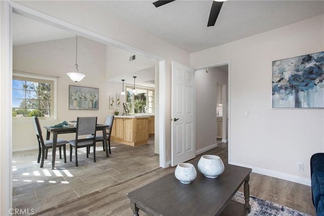 living area featuring ceiling fan, baseboards, wood finished floors, and plenty of natural light