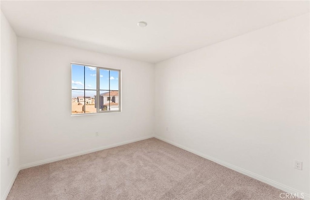 carpeted spare room featuring baseboards