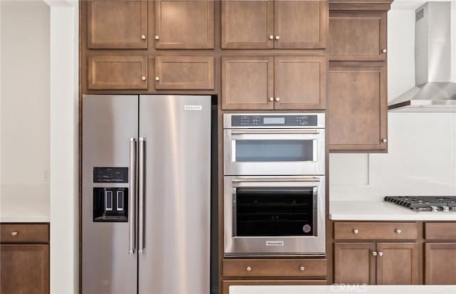 kitchen featuring appliances with stainless steel finishes, light countertops, and wall chimney range hood