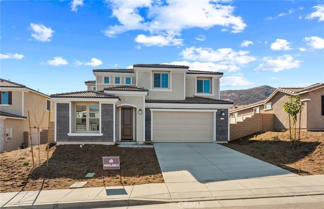 view of front of home with a garage, concrete driveway, a tile roof, fence, and stucco siding