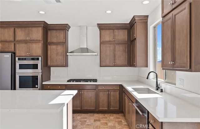 kitchen featuring appliances with stainless steel finishes, recessed lighting, a sink, and wall chimney exhaust hood