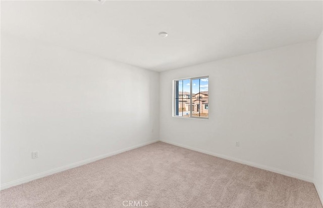 unfurnished room featuring light carpet and baseboards