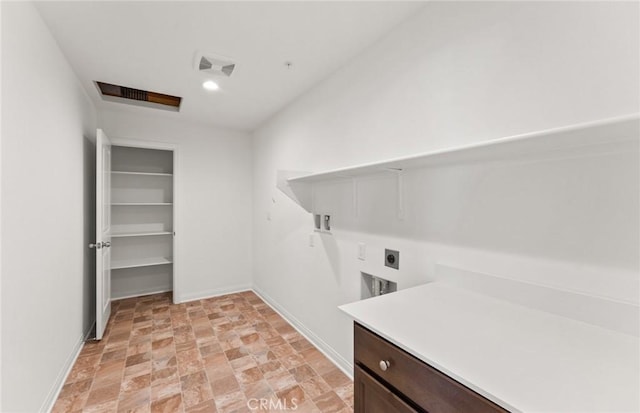 laundry area featuring laundry area, visible vents, baseboards, stone finish flooring, and electric dryer hookup