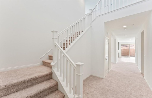 stairway featuring carpet, a high ceiling, and baseboards