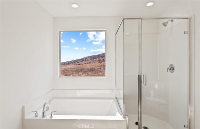 bathroom with a stall shower, a garden tub, and recessed lighting