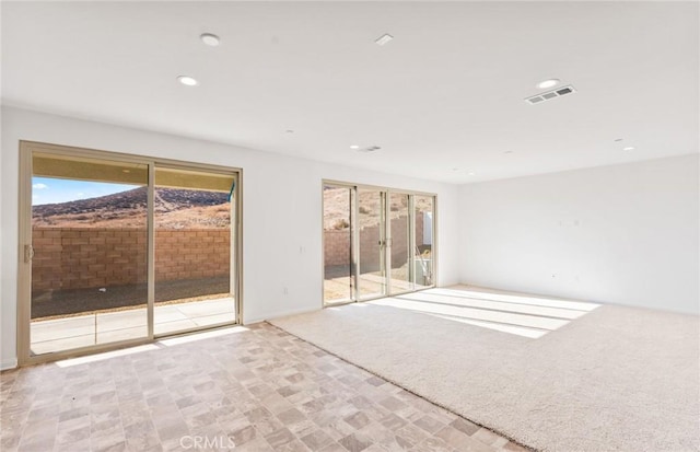 spare room with light carpet, visible vents, and recessed lighting