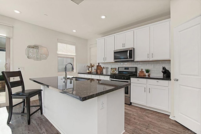 1510 Wildgrove Way, Vista, CA 92081 - kitchen featuring a kitchen island with sink, wood finished floors, a sink, appliances with stainless steel finishes, and decorative backsplash