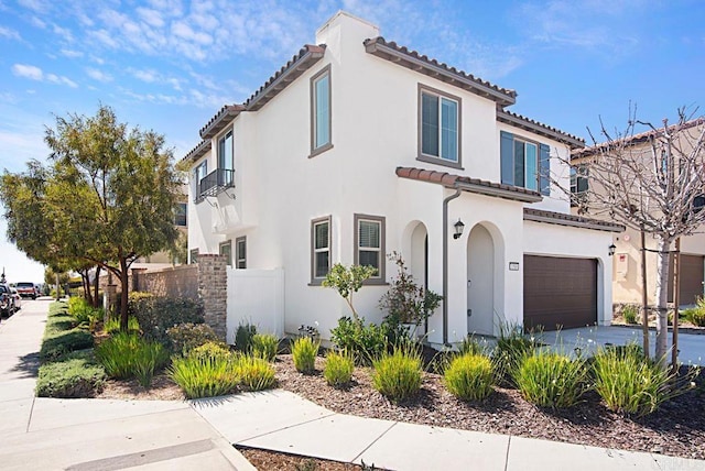 mediterranean / spanish home with driveway, an attached garage, fence, and stucco siding