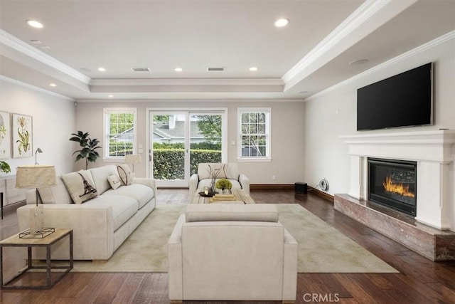 living area with visible vents, hardwood / wood-style floors, a raised ceiling, and a high end fireplace