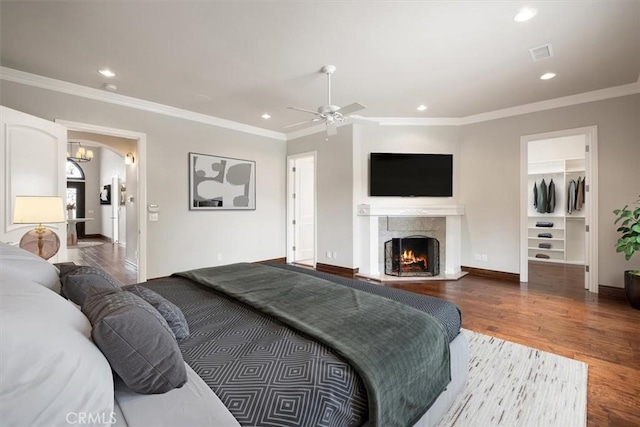 bedroom featuring baseboards, ornamental molding, wood finished floors, a fireplace, and recessed lighting