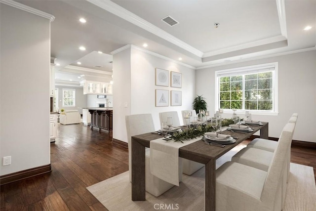 dining room featuring dark wood-style floors, baseboards, visible vents, and a raised ceiling