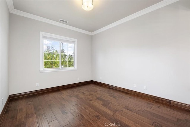 empty room featuring dark wood-type flooring, visible vents, crown molding, and baseboards