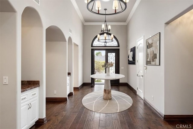 entryway with dark wood-type flooring, crown molding, and baseboards