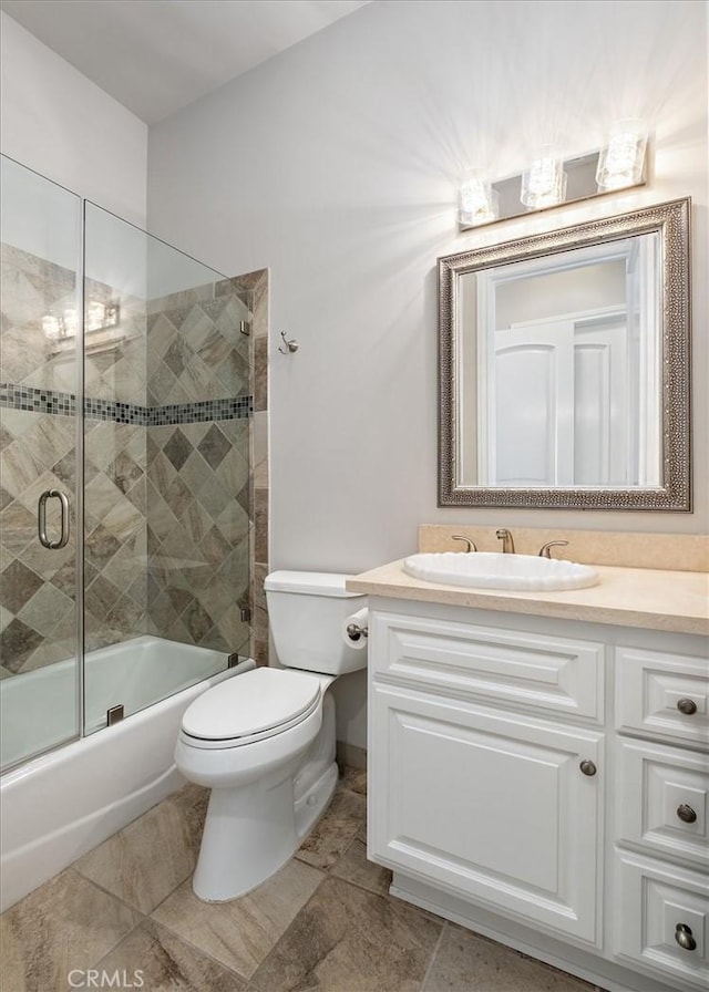 full bath featuring toilet, bath / shower combo with glass door, and vanity