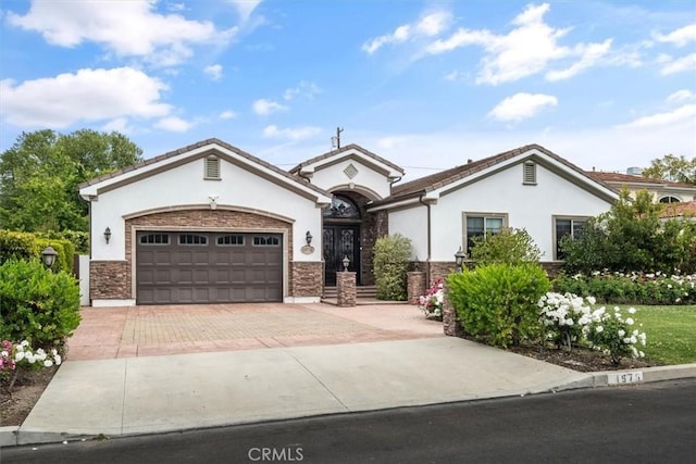 4976 Odessa Ave, Encino, CA 91436 - view of front facade featuring stucco siding, decorative driveway, an attached garage, and stone siding